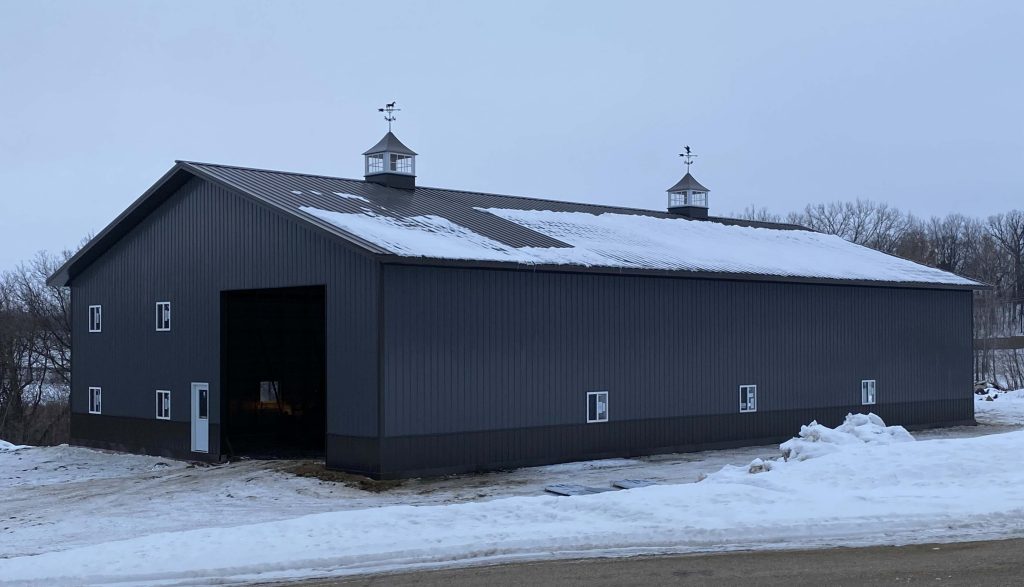 Large gray metal barn with snow-covered roof