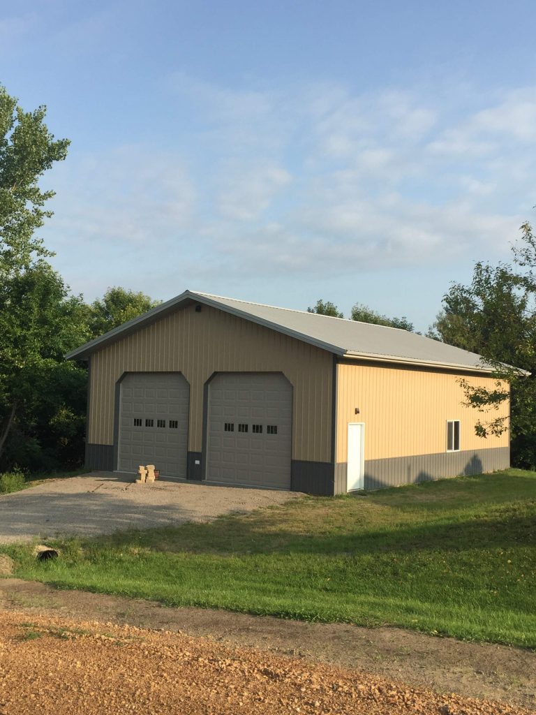 Beige metal garage with two doors and trees