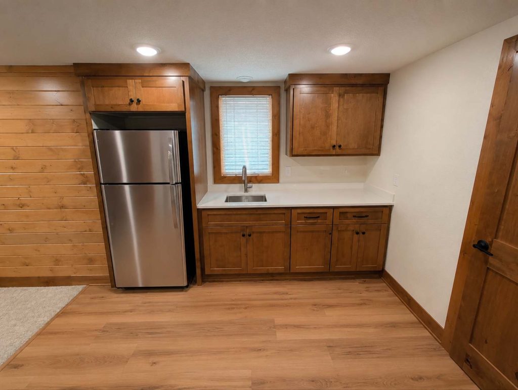 Small kitchenette with wooden cabinets and stainless refrigerator