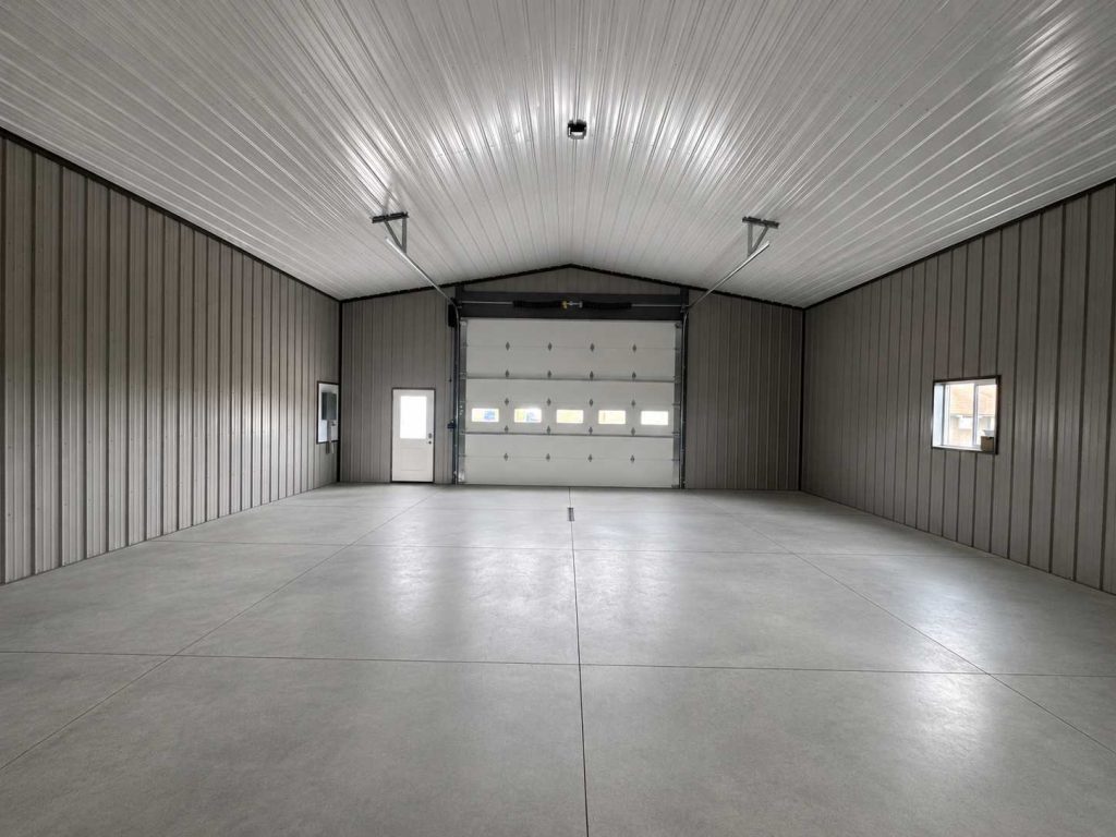 Spacious empty metal garage with concrete floor and roll-up door