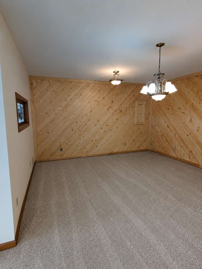 Empty room with wood-paneled walls and chandelier lighting