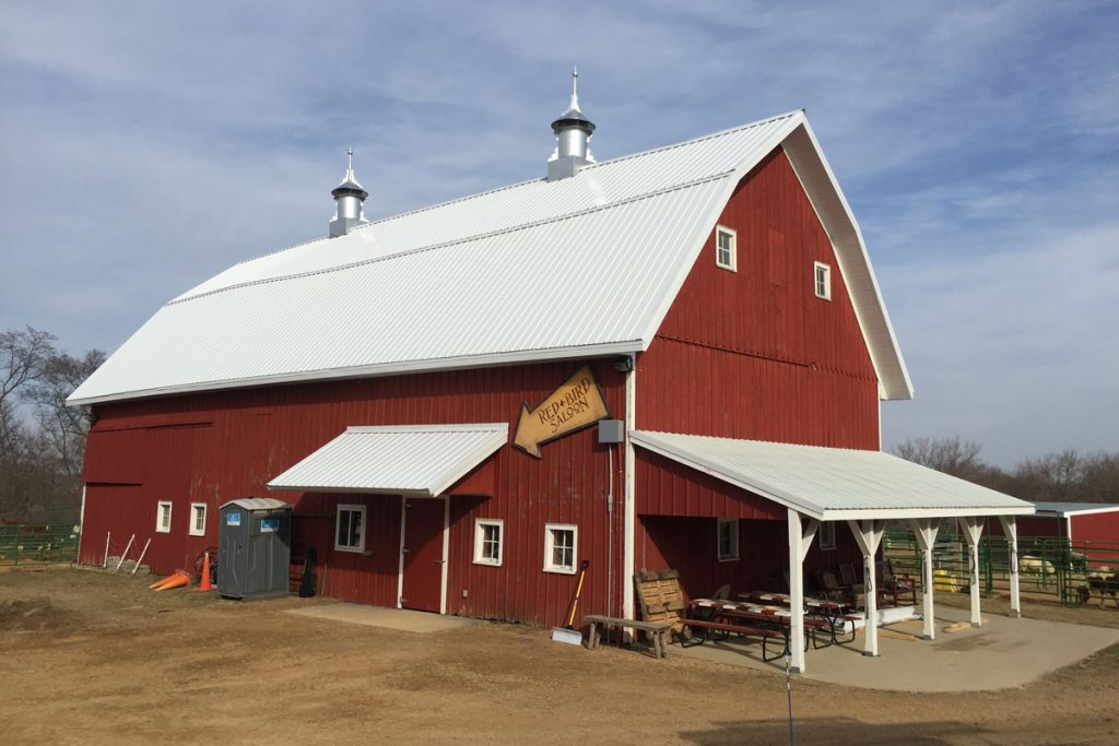 Red barn with white roof and picnic tables